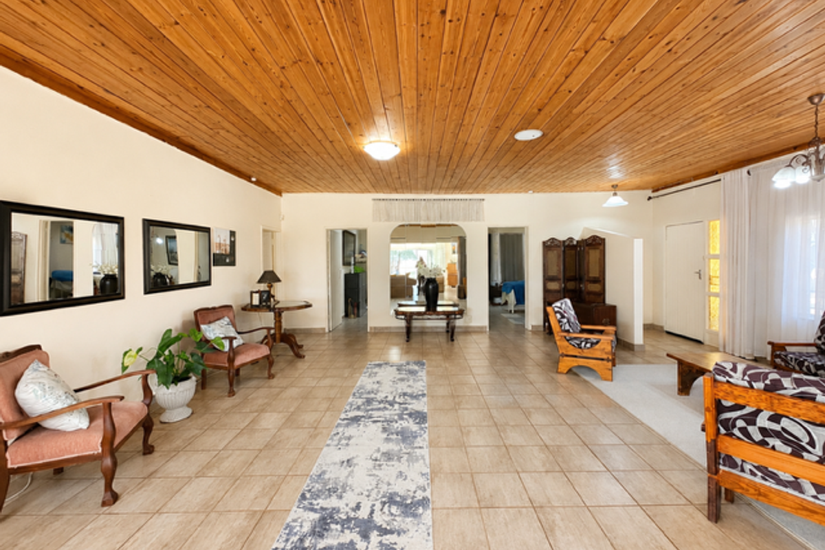 Spacious living area featuring a warm timber tongue and groove ceiling, neutral ceramic floor tiles, and an open-plan layout with an inviting archway.