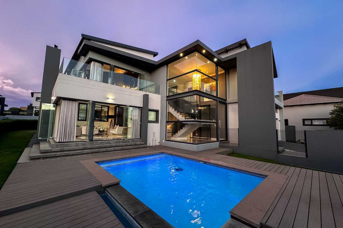 Modern double-story residence featuring expansive glass facades, a sleek swimming pool, and a spacious timber deck, perfect for contemporary outdoor living.