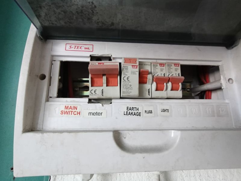 A close-up view of an electrical distribution board with visible circuit breakers and missing cover plates, indicating a need for maintenance.