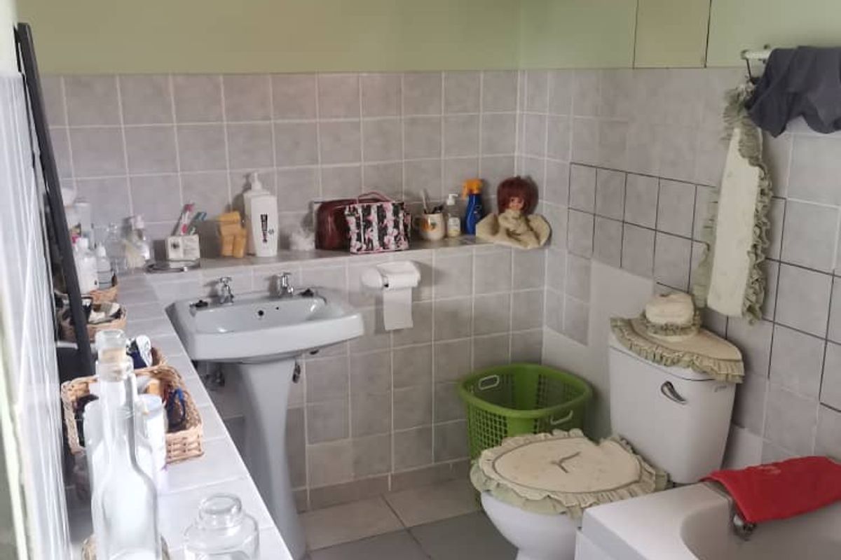 A functional bathroom featuring a pedestal sink, a standard toilet, and a tiled bathtub surround with neutral wall finishes.