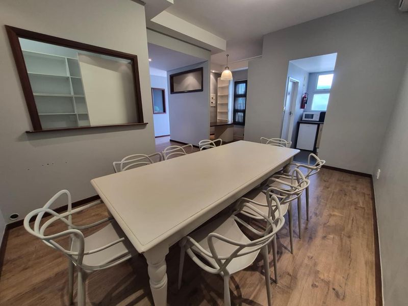 A well-lit office space featuring laminate flooring, built-in shelving units, and an internal window, providing a functional and professional work environment.