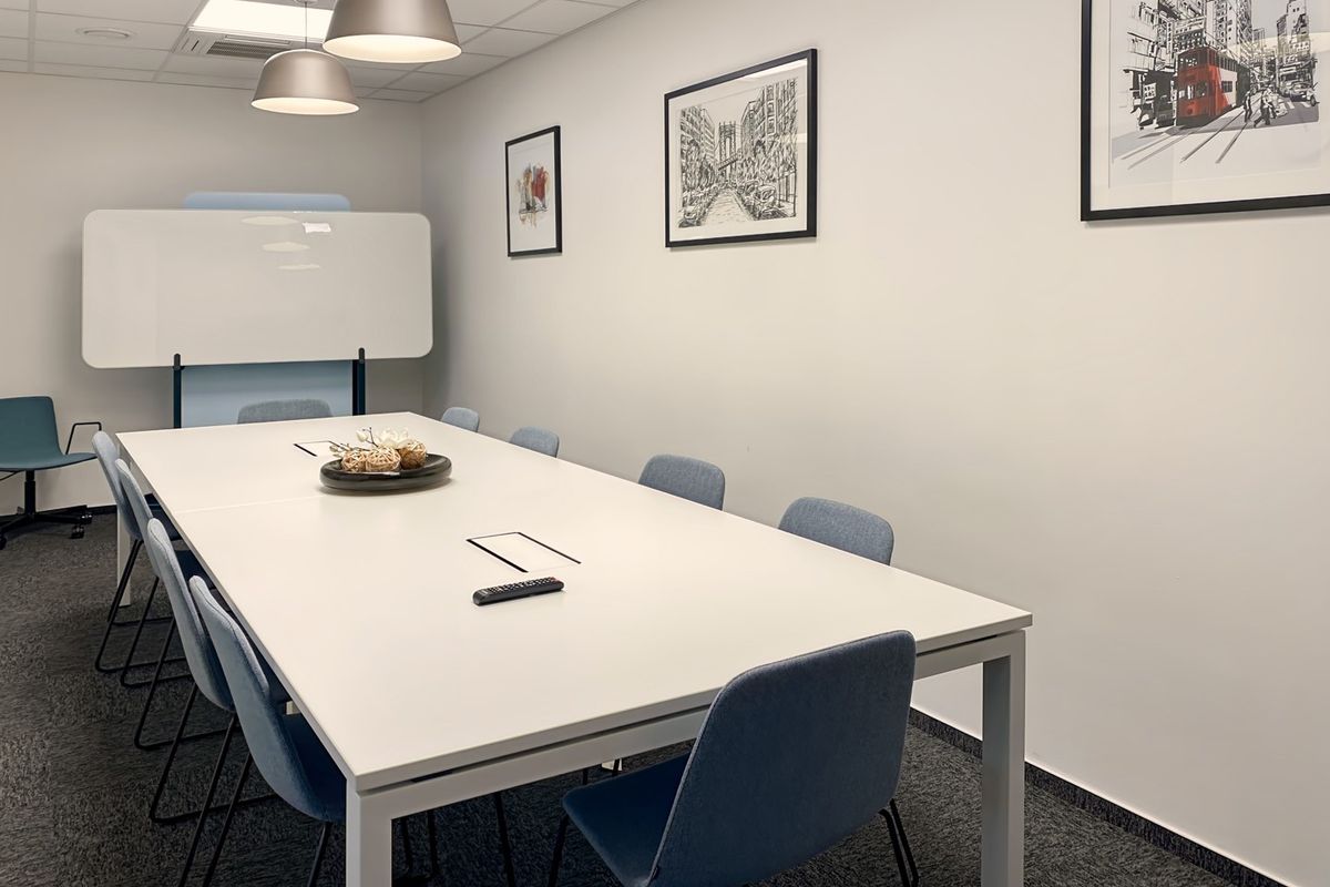 A modern, well-maintained office meeting room featuring a large conference table, suspended ceiling with recessed lighting, and professional carpeted flooring.