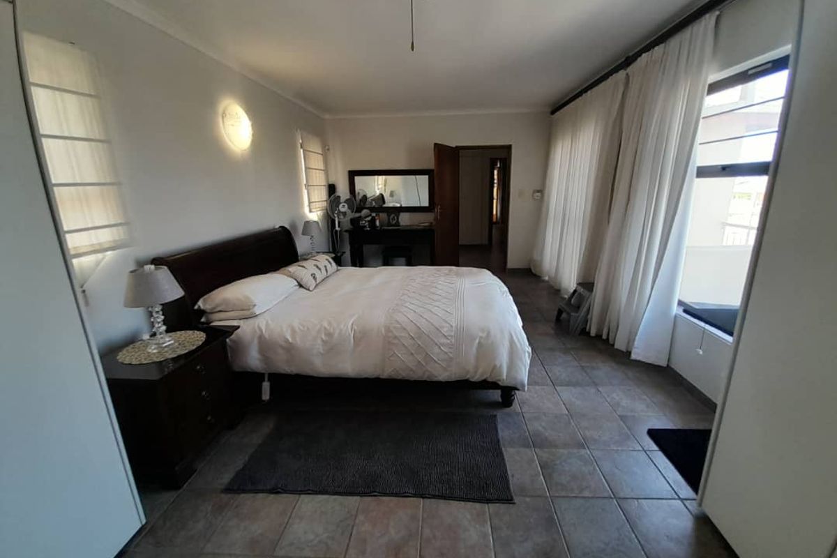 Spacious bedroom featuring tiled flooring, built-in cupboards, and large windows with natural light, providing a comfortable and functional living space.