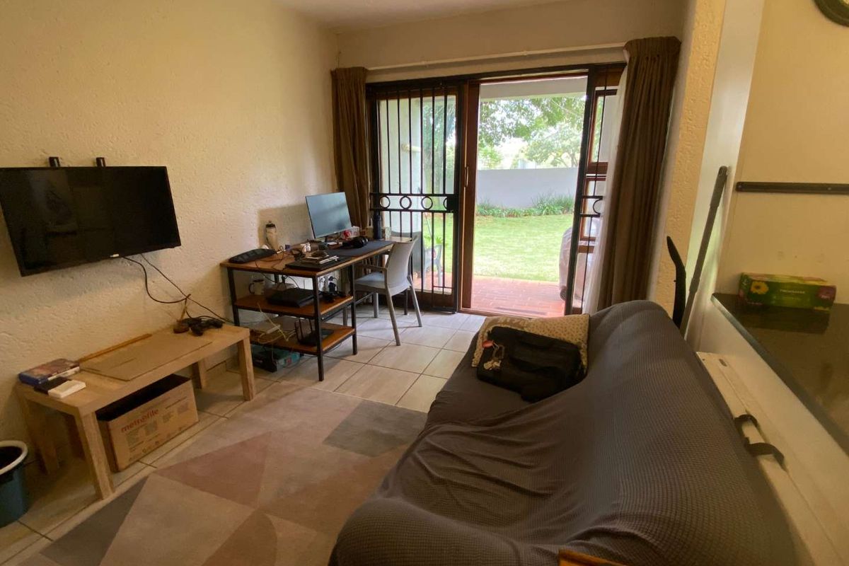 A living room featuring tiled flooring and a sliding door providing direct access to a private garden patio area.