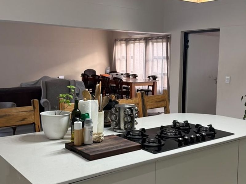 Modern open-plan kitchen featuring a central island with a built-in gas cooktop and contemporary pendant lighting, seamlessly flowing into the dining area.