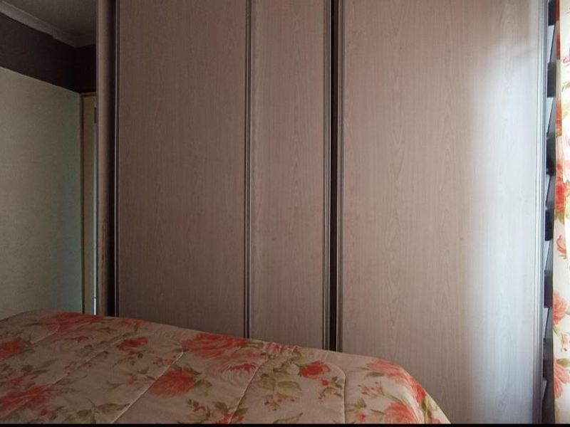 A bedroom featuring built-in cupboards with light wood-grain finish doors.