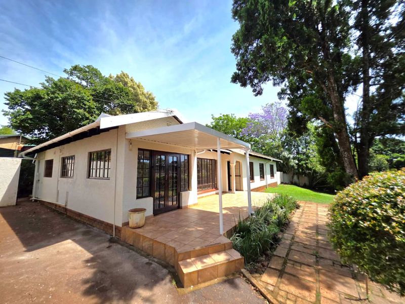 Rear view of the house featuring a tiled patio with a covered pergola, french doors, and a paved garden walkway.