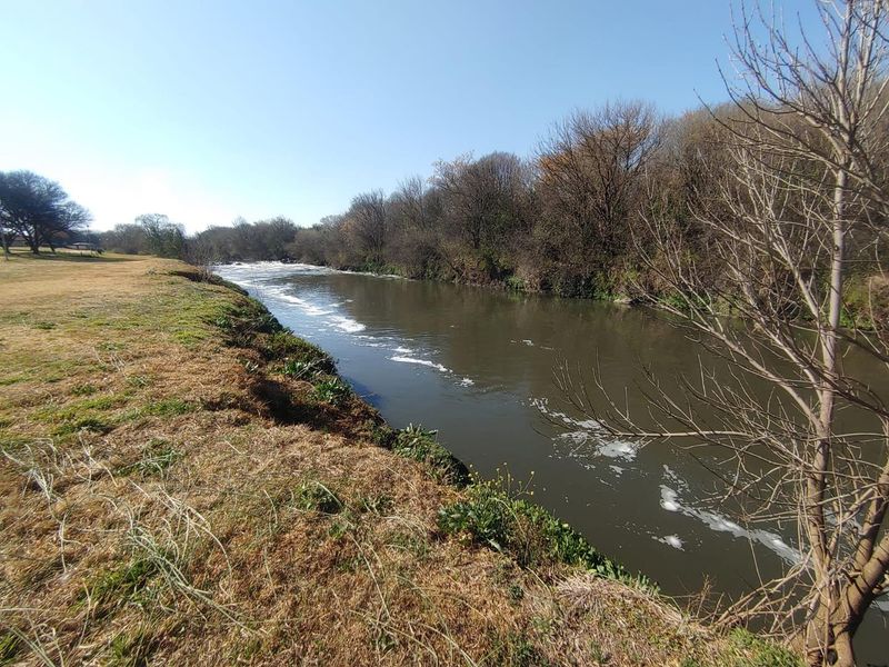 A scenic view of the river frontage bordering the residential land, featuring natural vegetation and open grassy banks.