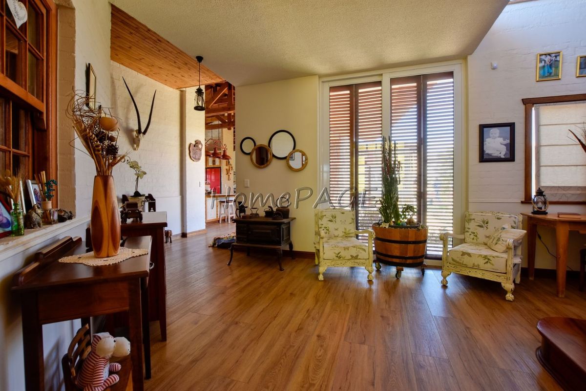 Spacious living area featuring warm laminate flooring, exposed timber ceiling beams, a skylight, and large sliding doors providing access to the outdoors.