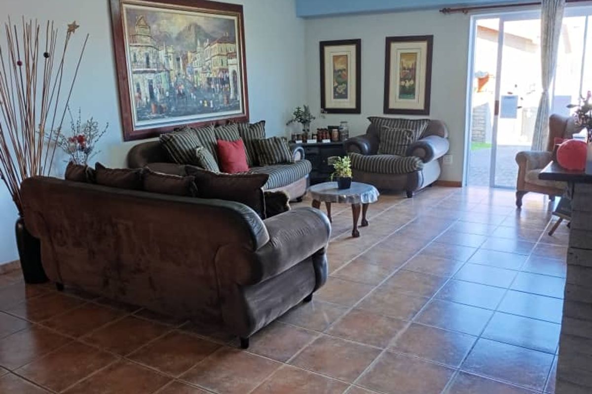 Spacious living area featuring ceramic floor tiles, cove molding, and a sliding glass door providing access to the exterior.