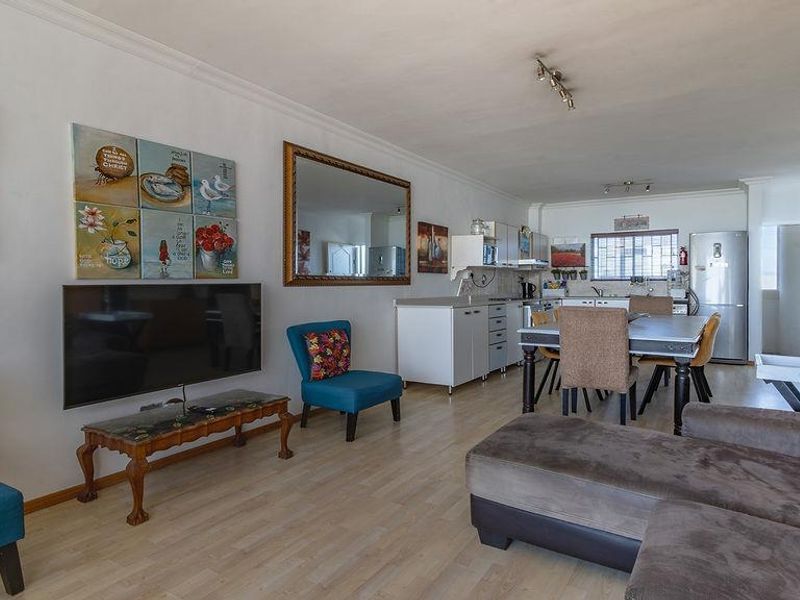 Open-plan living and dining area featuring laminate flooring and a functional kitchen space with built-in cabinetry.