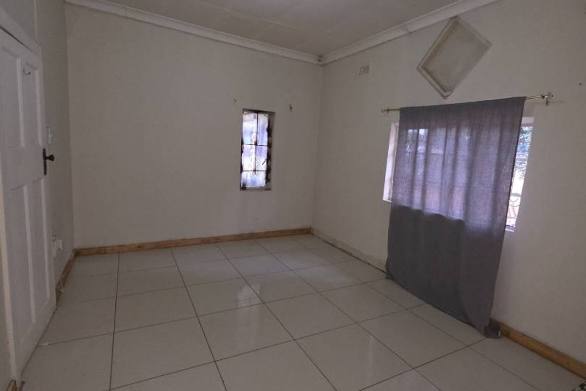 An empty bedroom featuring tiled flooring and ceiling cornicing, currently requiring minor repairs to the floor and wall finishes.