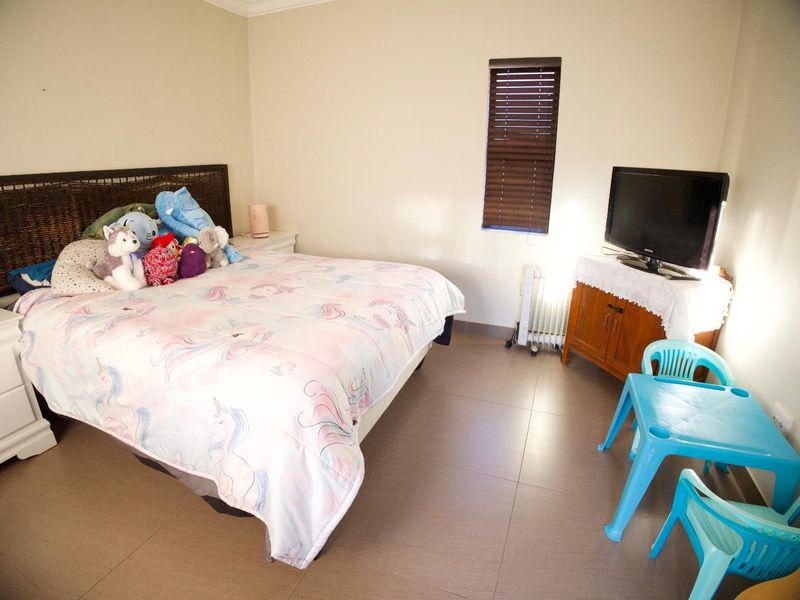 A functional bedroom featuring tiled flooring and venetian blinds, providing a neutral base for personalization.