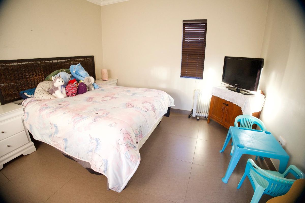 A functional bedroom featuring tiled flooring and venetian blinds, providing a neutral base for personalization.