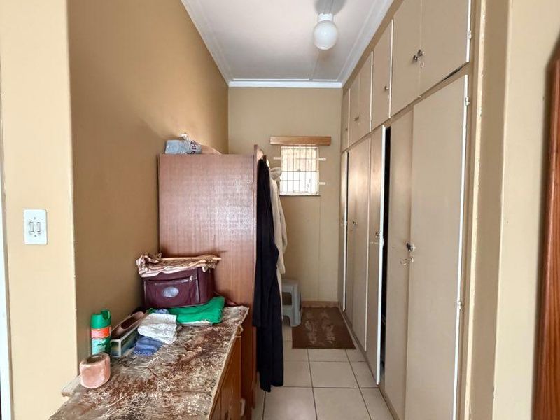A functional hallway featuring extensive built-in cupboard storage and neutral tiled flooring, providing practical access and storage space.