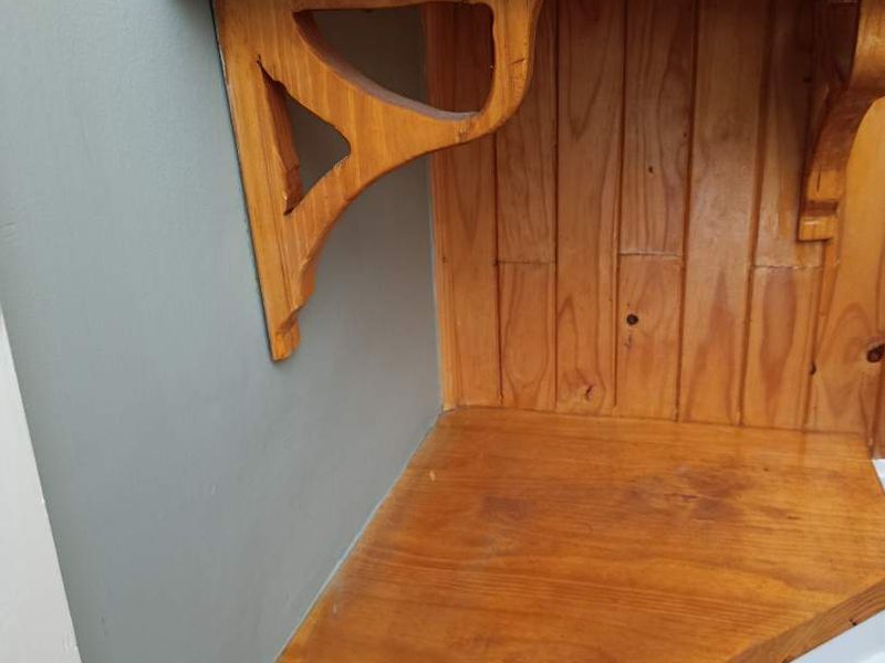 A close-up view of built-in timber corner shelving featuring decorative brackets and vertical timber wall panelling.