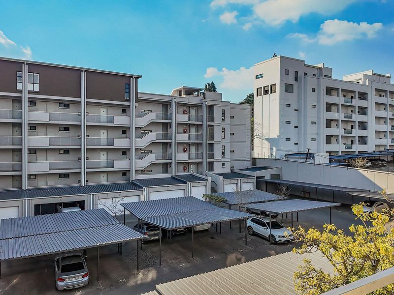 View of the apartment complex exterior featuring multi-level residential units, covered parking bays, and external staircases.