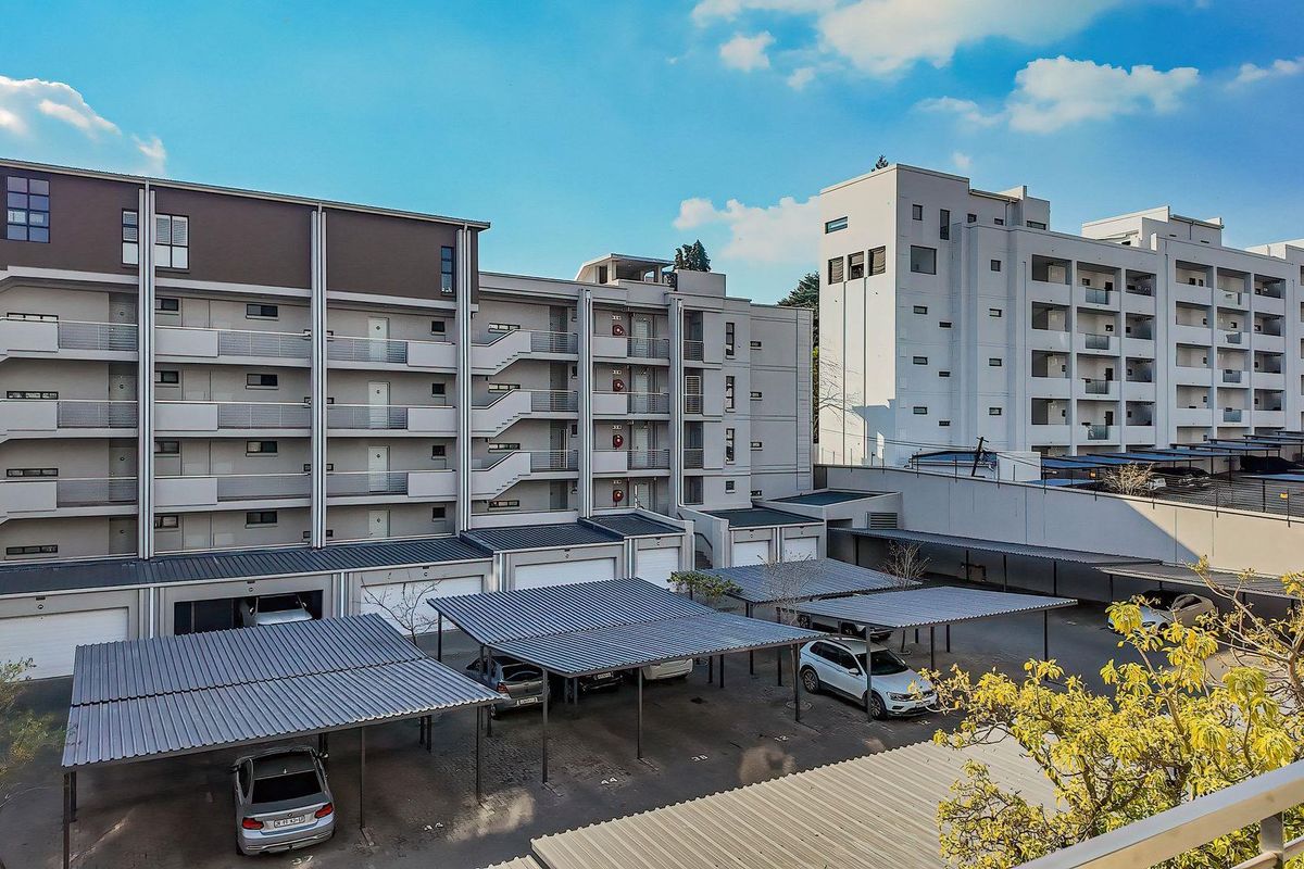 View of the apartment complex exterior featuring multi-level residential units, covered parking bays, and external staircases.