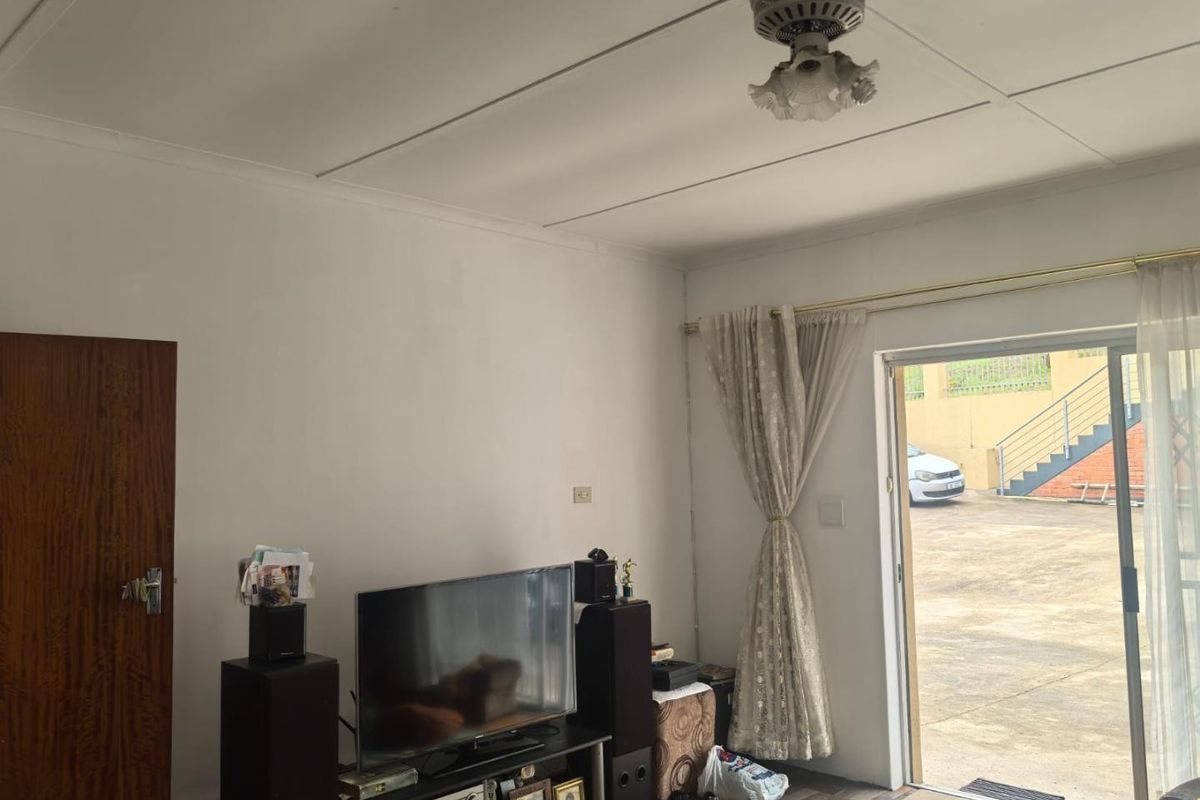 Living room featuring a ceiling fan and sliding glass door providing access to the exterior paved area.