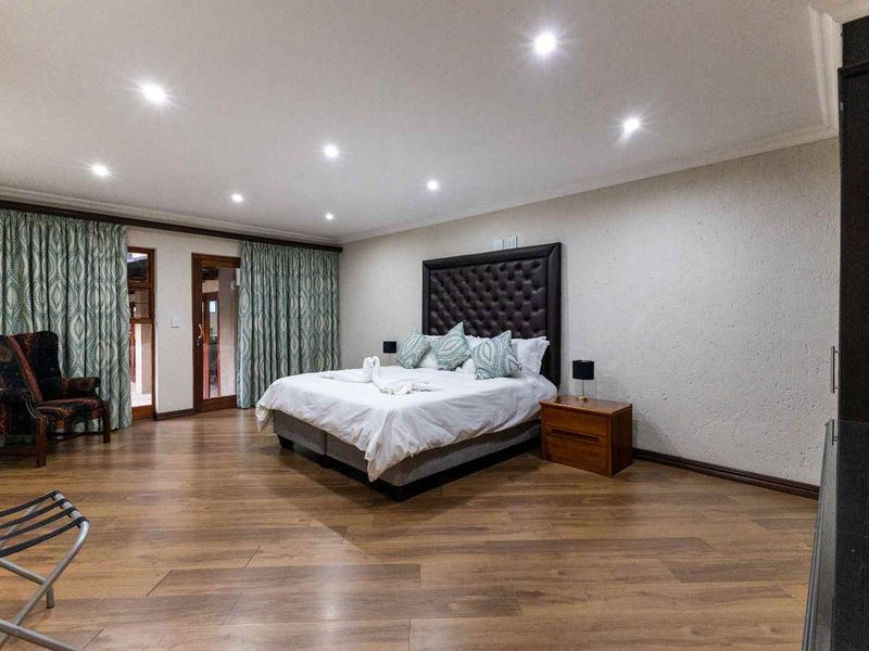 Spacious bedroom featuring laminate flooring, recessed downlighting, and sliding glass doors providing access to the exterior.