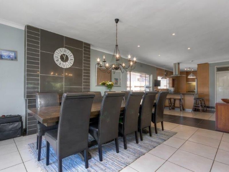 Spacious open-plan living and dining area featuring a tiled floor, a modern feature fireplace, and a well-integrated kitchen with an island.