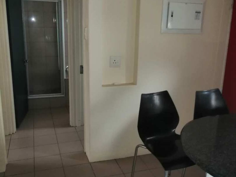 A functional hallway area featuring tiled flooring, a recessed wall niche, and access to an adjacent bathroom.