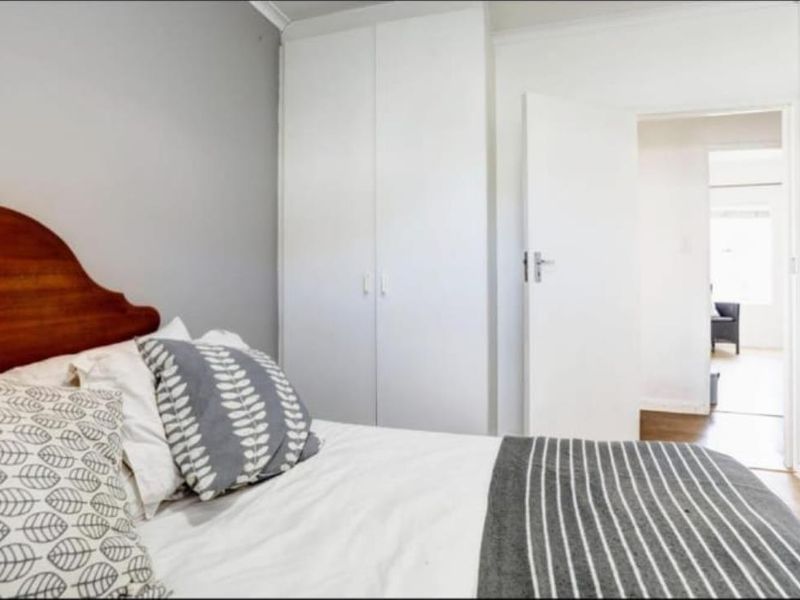 A well-maintained bedroom featuring neutral walls, laminate flooring, and a built-in wardrobe, offering a clean and functional living space.