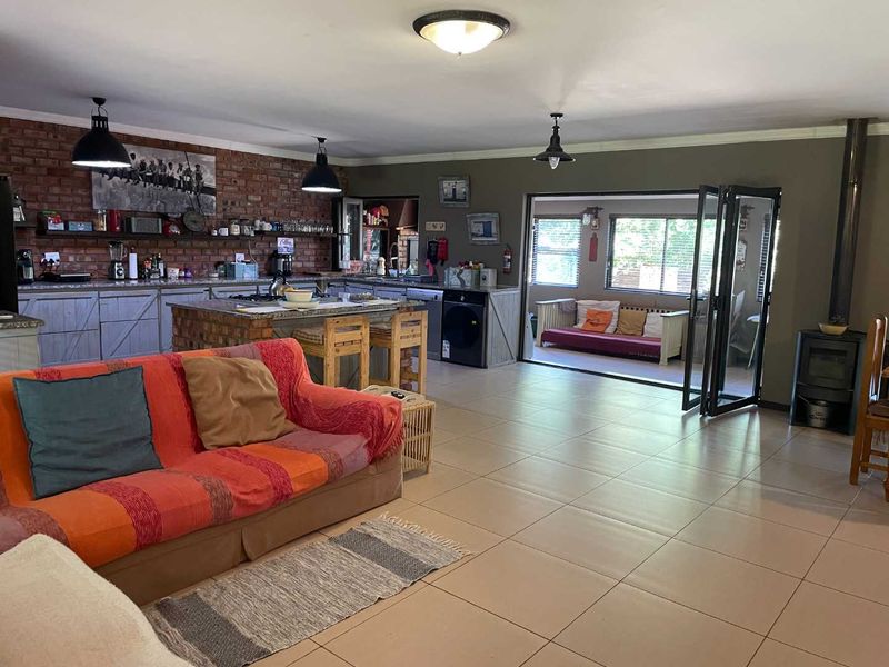 Spacious open-plan living area featuring a kitchen with exposed brick walls, a central island, and seamless flow to an outdoor patio through bi-fold doors.