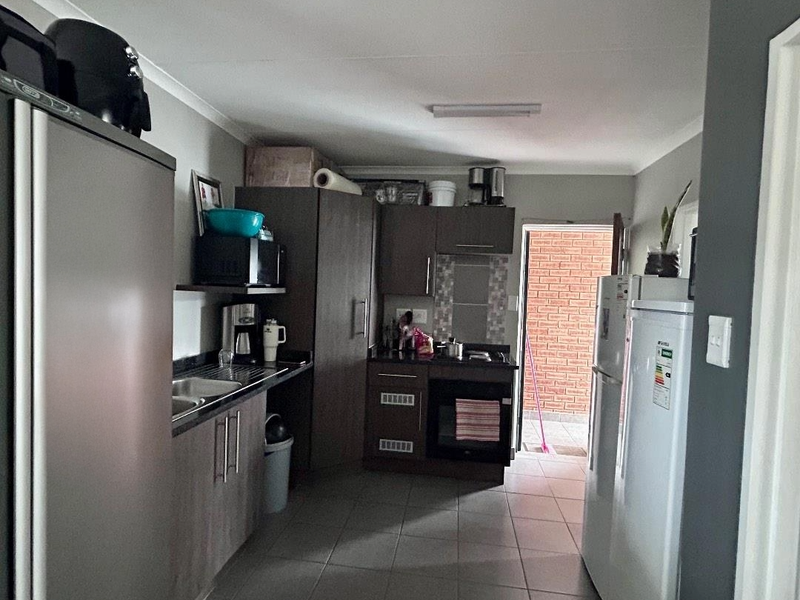A functional kitchen featuring built-in cabinetry, laminate countertops, a built-in oven, and tiled flooring, with direct access to an outdoor area.