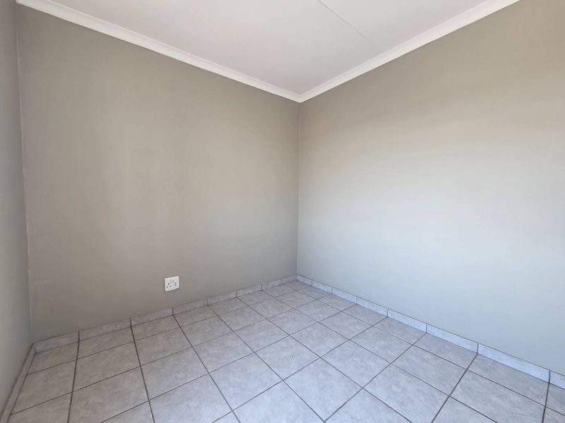 A clean, empty bedroom featuring neutral wall paint, tiled flooring, and coved ceiling cornices, providing a versatile space ready for personalization.
