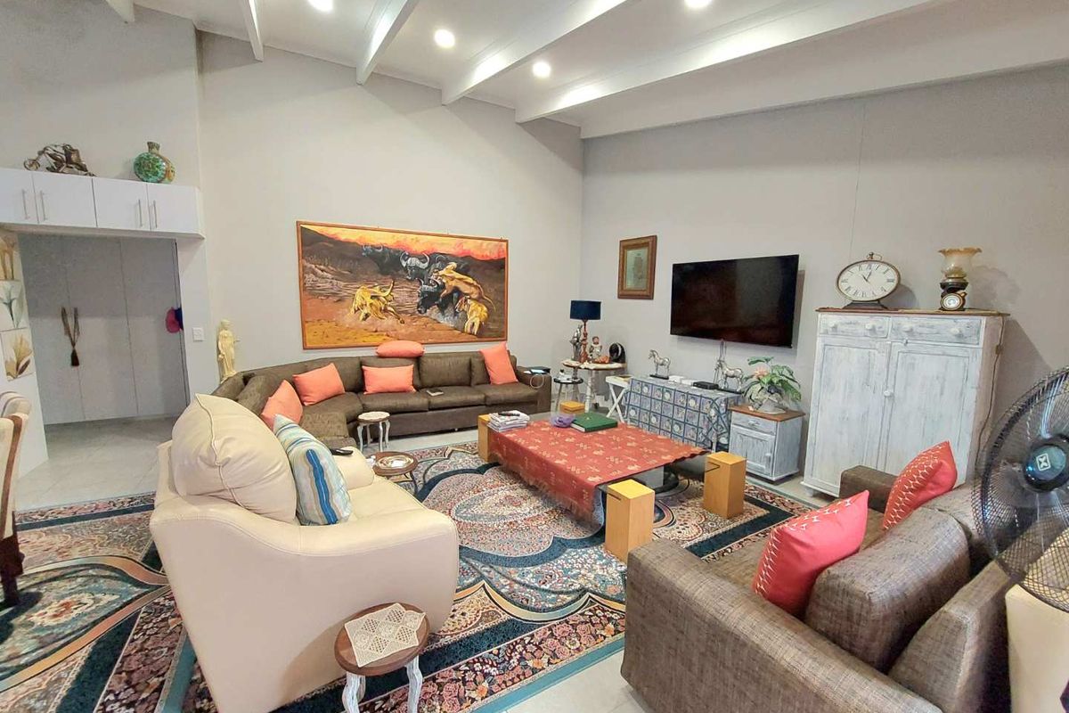 Spacious living room featuring high vaulted ceilings with exposed beams, recessed lighting, and tiled flooring, creating an open and airy atmosphere.