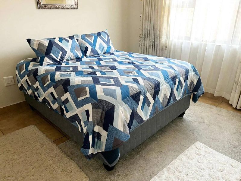 A functional bedroom featuring tiled flooring and natural light through window treatments, providing a neutral base for personal styling.