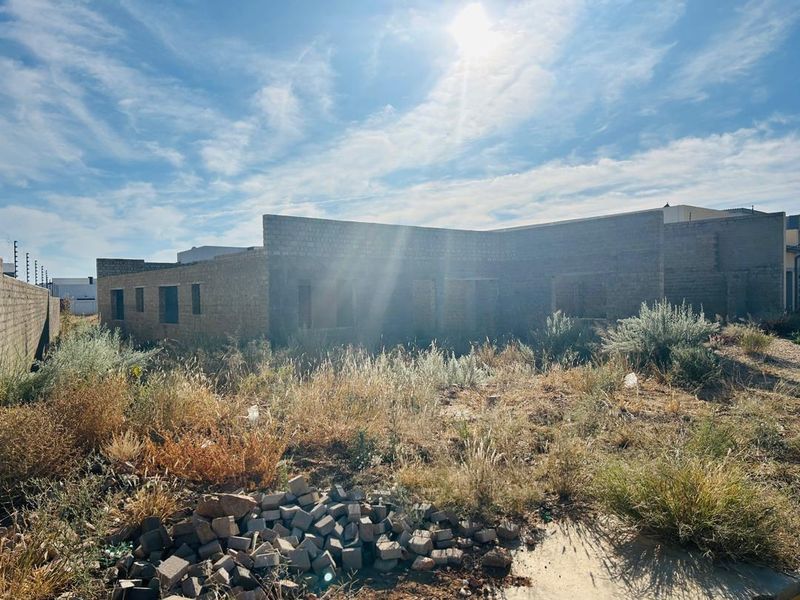 A view of a residential property currently under construction, featuring exposed masonry walls and an overgrown site requiring significant development.