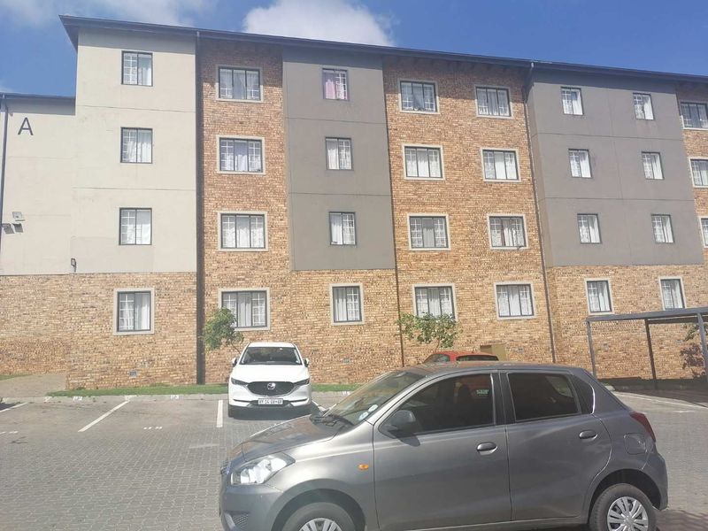 Front elevation of a multi-story townhouse complex featuring a brick and rendered facade with dedicated paved parking bays.