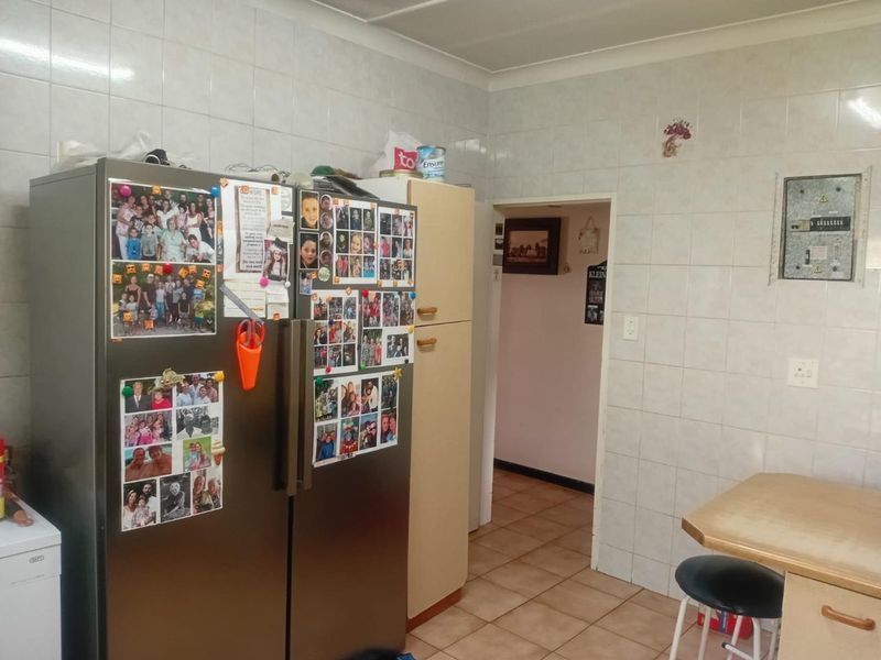 A functional kitchen area featuring tiled walls, tiled flooring, and built-in cabinetry, providing a practical space with potential for cosmetic updates.