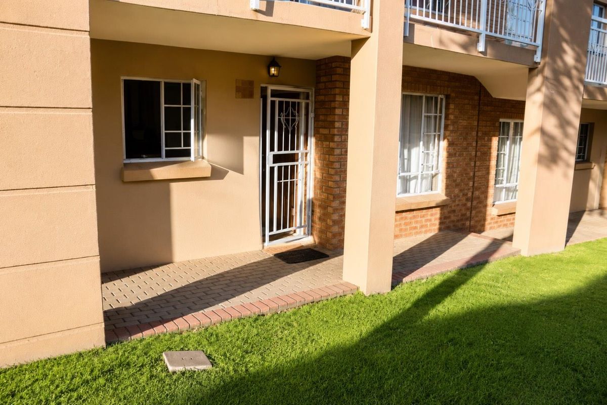 Ground floor apartment exterior featuring a paved patio area, brick facade, and secure entrance gate with direct access to the garden.