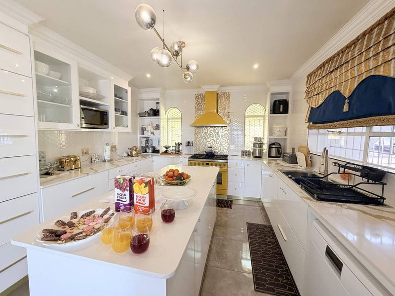 Modern, well-appointed kitchen featuring a central island, high-end cabinetry, quartz countertops, and integrated appliances with a distinctive yellow range hood.