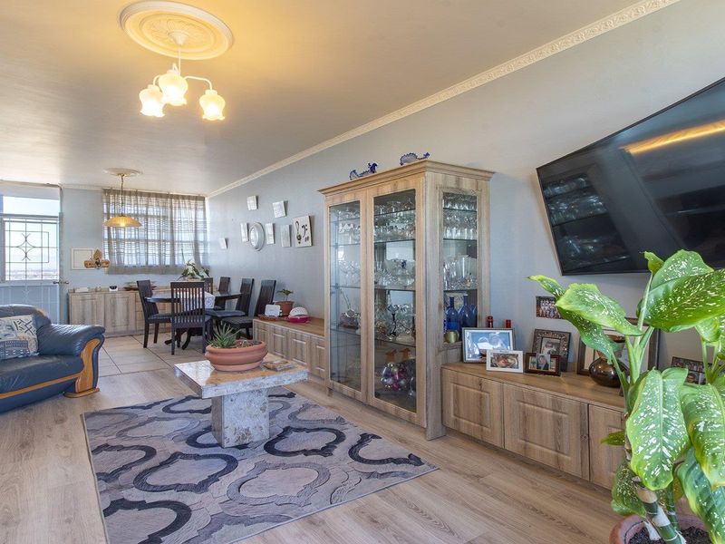 Spacious open-plan living and dining area featuring laminate flooring, decorative ceiling roses, and coving, providing a versatile layout for comfortable daily living.