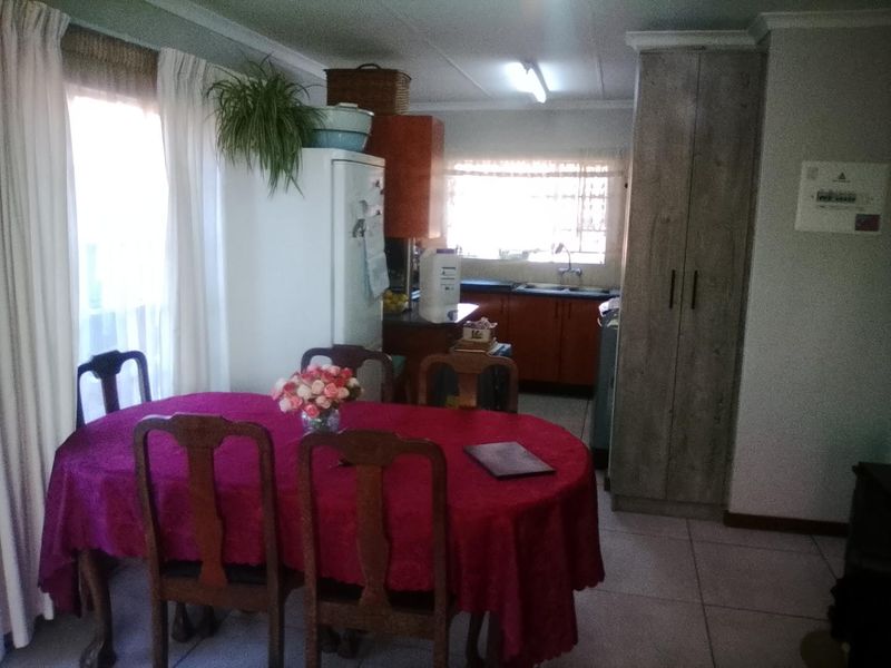 Open plan living and dining area featuring tiled flooring and a functional kitchen with built-in cabinetry and sink.