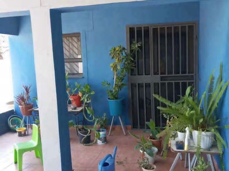 A covered patio area featuring tiled flooring and a secure metal entrance gate, providing a functional outdoor transition space.