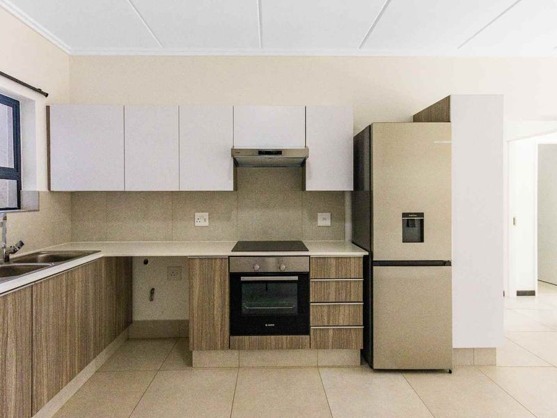 Modern kitchen featuring sleek cabinetry, stone countertops, integrated oven and hob, and tiled flooring in a clean, neutral space.
