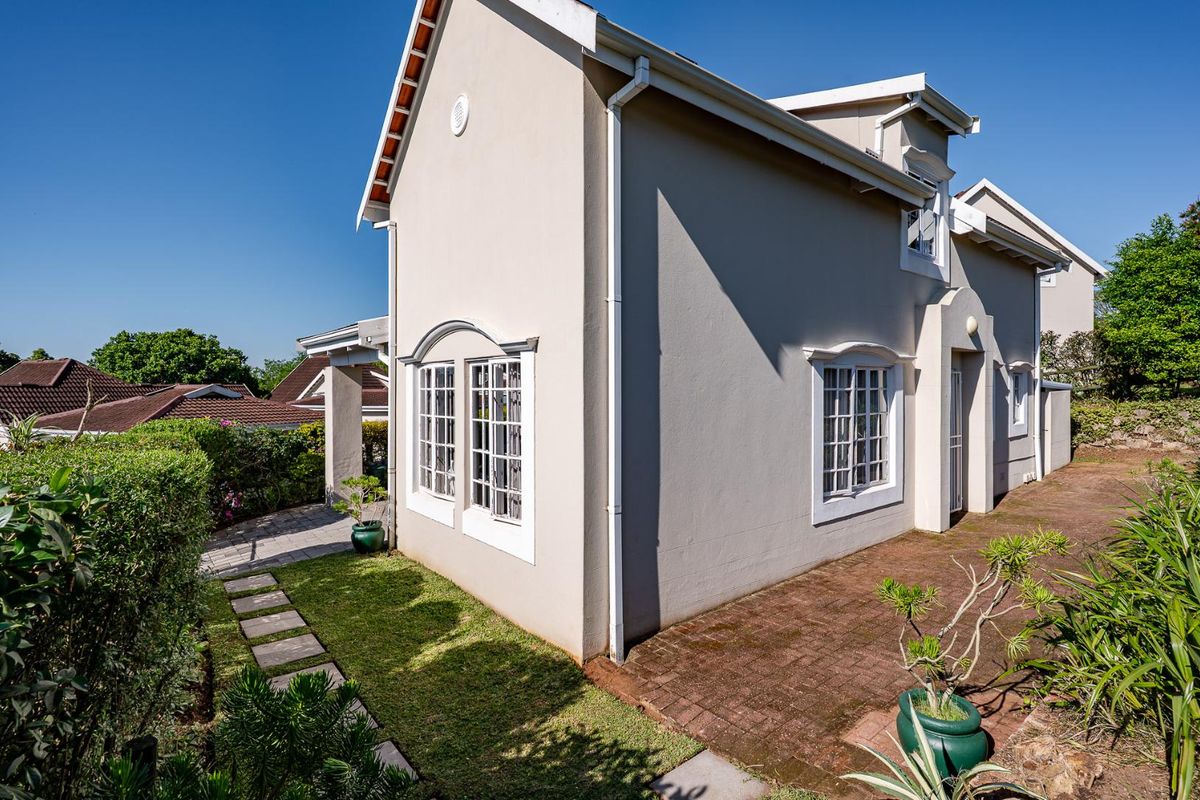 Side view of the townhouse exterior featuring a paved walkway, manicured lawn, and classic window detailing with white frames.