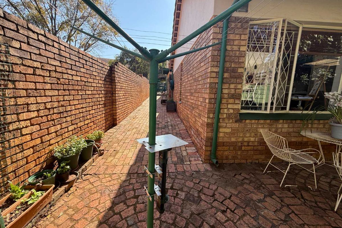 A side passage featuring brick paving and a high brick boundary wall, providing a secure and private outdoor walkway along the side of the house.