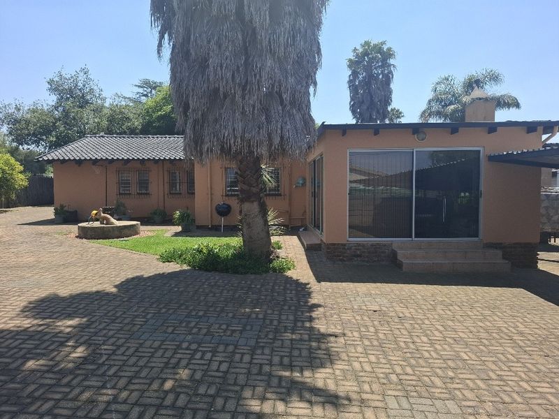 Rear view of the property featuring a paved courtyard, sliding glass doors, and a tiled roof structure.