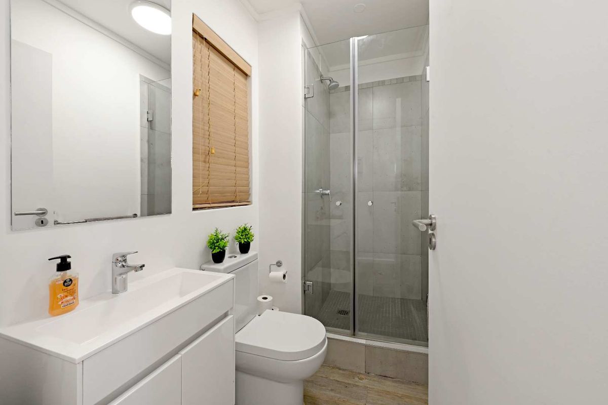 A modern, well-maintained bathroom featuring a sleek vanity, a glass-enclosed shower with tiled finishes, and a wall-mounted mirror.