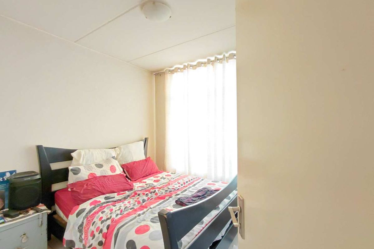 A compact bedroom featuring a window with natural light, standard ceiling finish, and neutral wall tones.