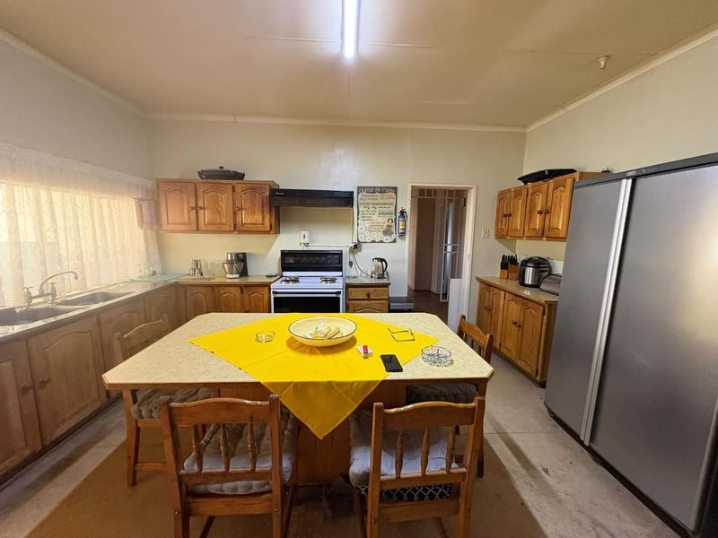 A functional kitchen featuring traditional wooden cabinetry, laminate countertops, a double basin sink, and a freestanding stove with an extractor fan.