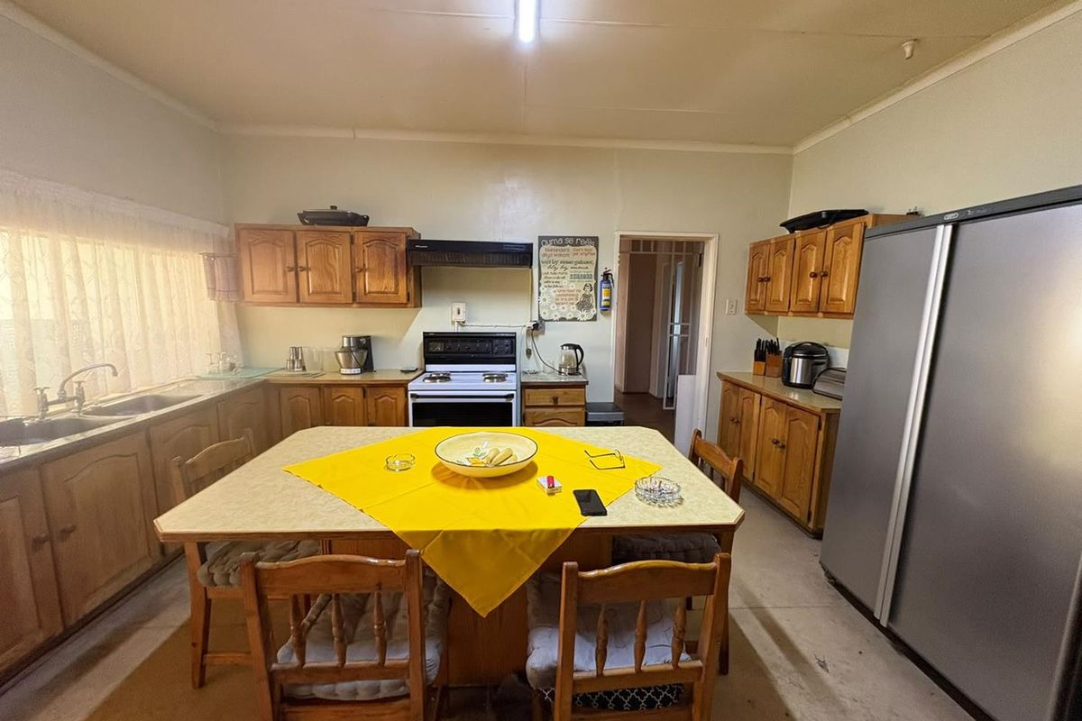 A functional kitchen featuring traditional wooden cabinetry, laminate countertops, a double basin sink, and a freestanding stove with an extractor fan.