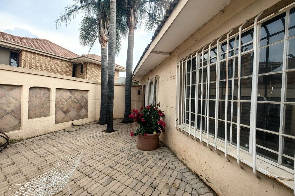 A paved rear courtyard area featuring boundary walls and security-barred windows, offering a private outdoor space with potential for landscaping improvements.