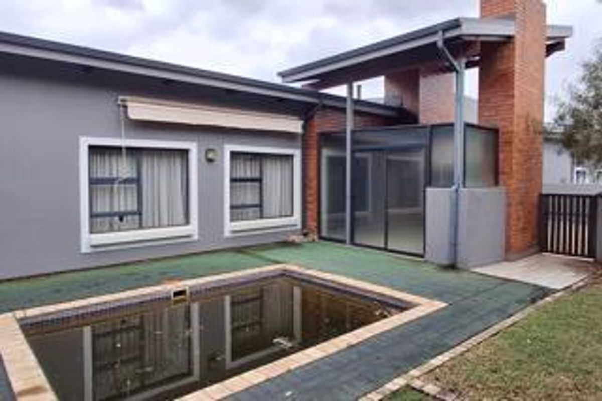 Rear exterior view of the townhouse featuring a swimming pool, brick chimney, and sliding glass doors leading to the living area.